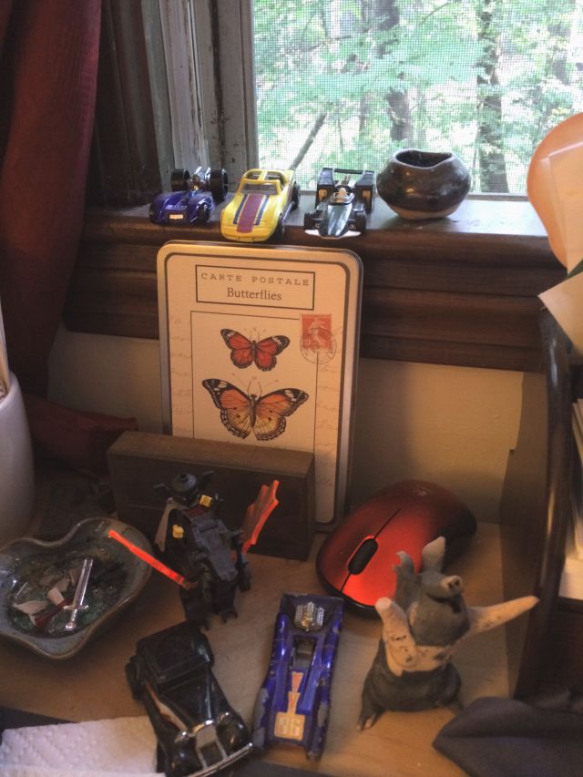 part of my collection of toy cars lined up in a row, science-inspired postcards, and figurines