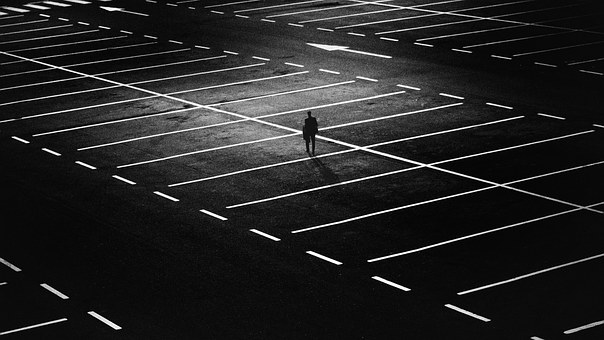 person walking across an empty parking lot